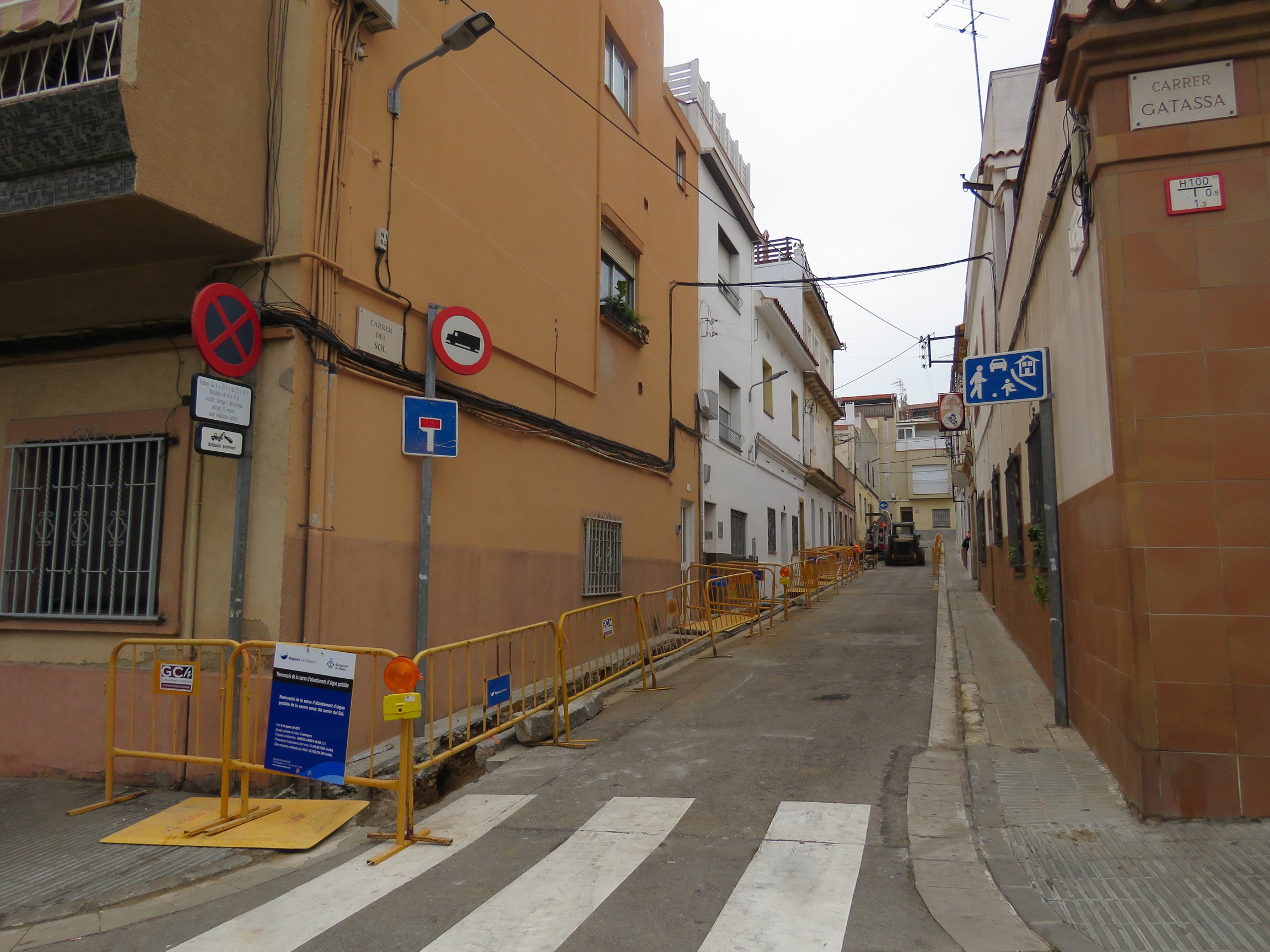 Carrer del Sol en obres amb tanques grogues d'obres a la banda dreta i cartell d'Aigües de Mataró en primer plà.