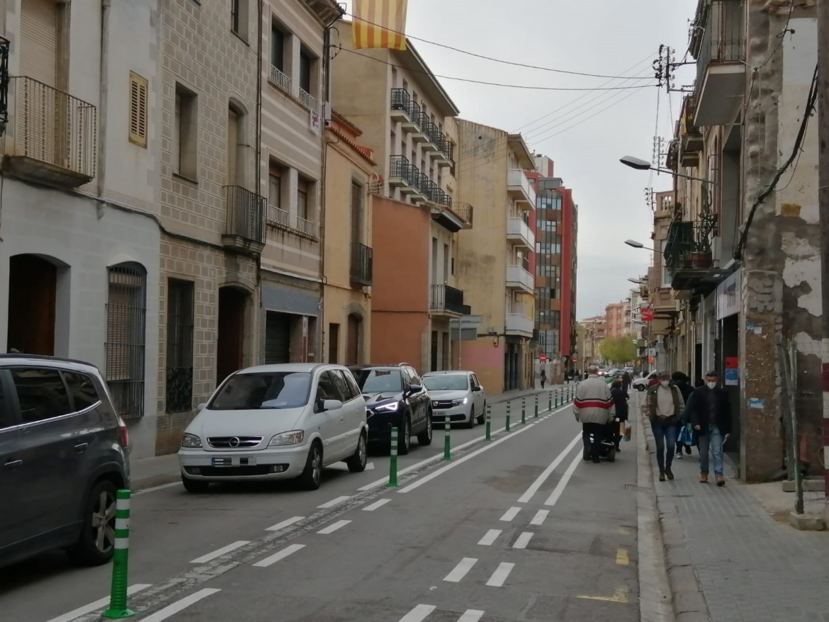 Camí Ral de la Mercè on es veu filera de cotxes a la calçada i vianants caminant per la vorera.
