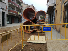 Camí Ral amb terra de sorra, primer pla d'una tanca d'Aigües de Mataró i tubs de grans diàmetres, de canalitzacions d'aigua al darrera la tanca