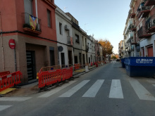 Imatge del Rierot amb tanques situades a l'esquerra, dos contenidors d'obres a la dreta i escultura de la plaça del Forn del Vidre al fons