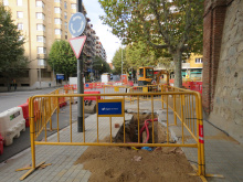 Rasa oberta a la vorera del carrer de Mata amb tanca d'obres d'Aigües de Mataró en primer pla i tubs de les canalitzacions a la vista