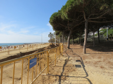 Passeig del Callao amb tanques d'obres al costat de la platja i banyistes a la sorra