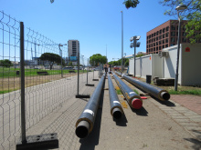 Canonades de TubVerd situades al costat d'una tanca de reixa. Rotonda de la Porta Laietana i edifici TecnoCampus al fons