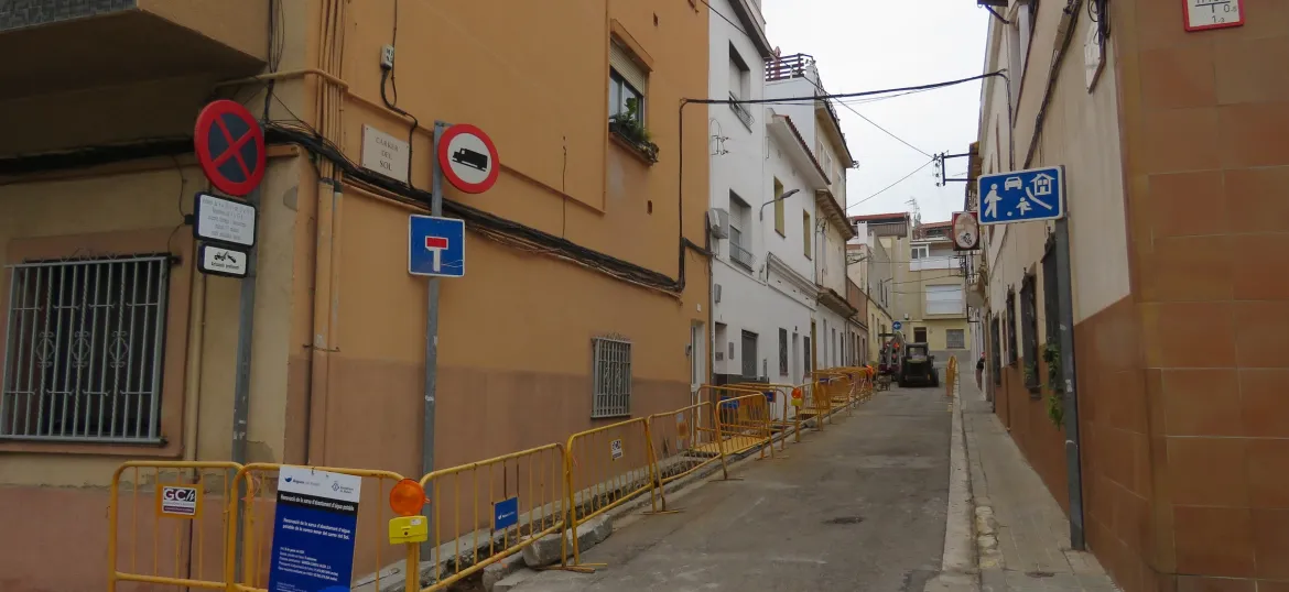 Carrer del Sol en obres amb tanques grogues d'obres a la banda dreta i cartell d'Aigües de Mataró en primer plà.