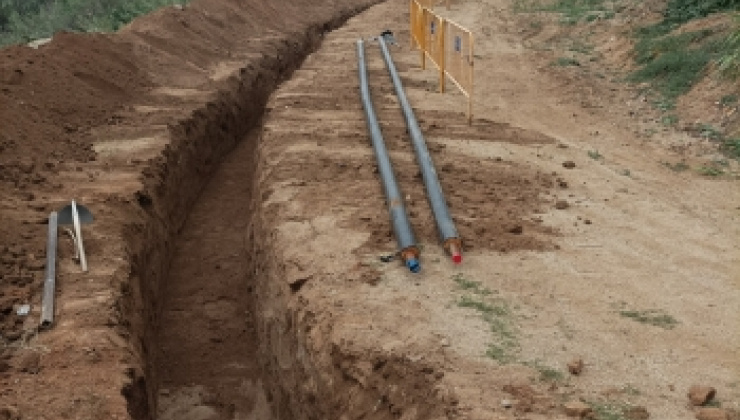 Rasa oberta enmig d'un terreny amb canonades de Tubverd a punt per instalar a la dreta i tanques d'obra